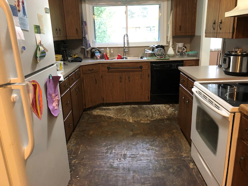 Buckled and stained kitchen subfloor after a water leak